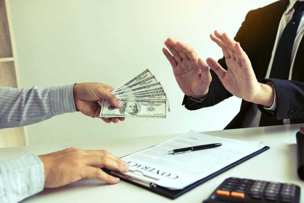 Businessperson refusing cash during a contract discussion