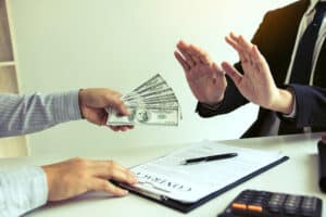 Businessperson refusing cash during a contract discussion